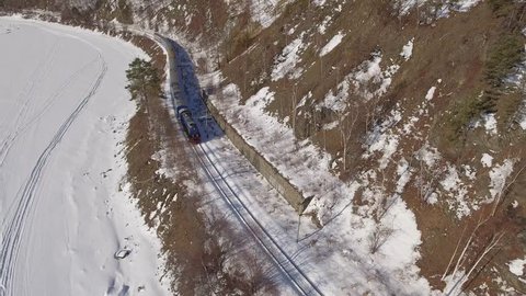 Passengers train Trans Siberian railway. Frozen lake Baikal coast. Winter beautiful Holiday  Russia. Sunny day snow field high rocks. Fast speed aerial drone 4k footage.