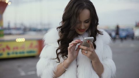 Happy rich woman using smartphone on a street. 4K