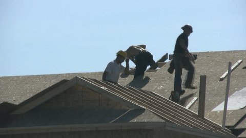Construction Workers Building The Roof On A New Home