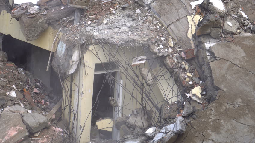 the process of destruction of the old building with heavy machinery.