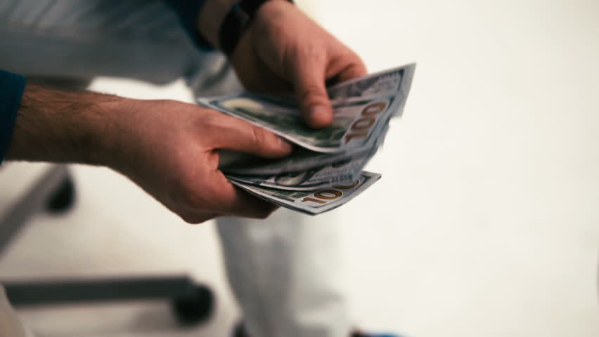The man counts the American dollars. Money in men's hands. A man holds one thousand dollars in his hands. The employee received wages in cash. Unexpected win. The fee for the work done.Time is money. Royalty-Free Stock Footage #32559616