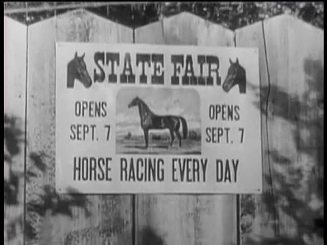 Zoom in shot of horse race poster on wooden fence
