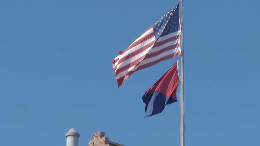 USA American flag and red and black flag of Anarchist Communism political movement waiving in breeze 