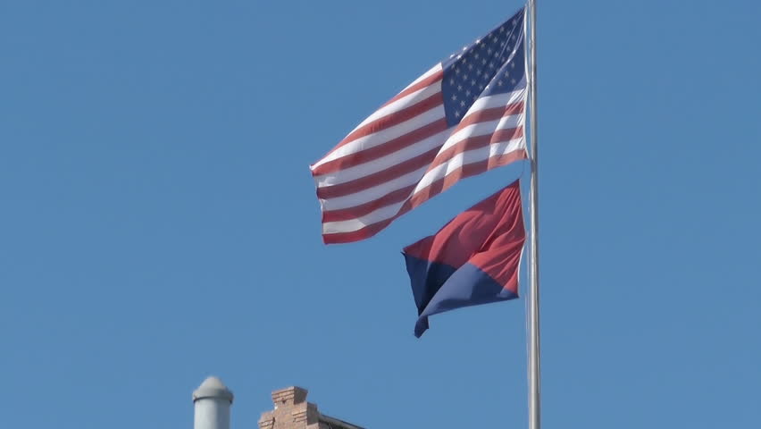 USA American flag and red and black flag of Anarchist Communism political movement waiving in breeze 