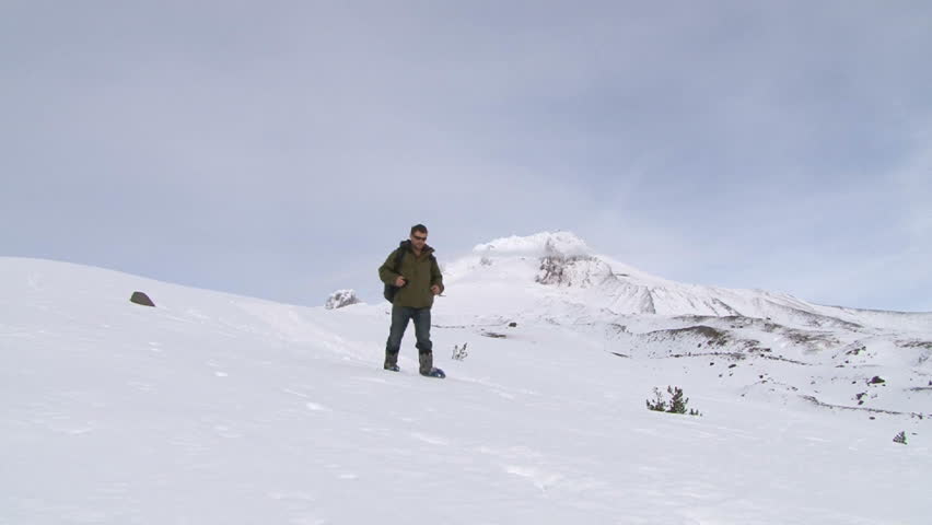 Model released man with snow shoes hikes down snowy Mount Hood / Mt Hood in