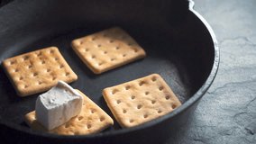 Laying a marshmalla hand out of a bowl on biscuits in a hot pan