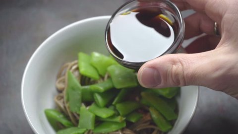 Pouring soy sauce into buckwheat noodles with beans
