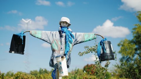 A scarecrow against a blue sky with clouds. Keeps the garden from birds and other pests