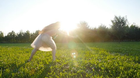 Young woman doing a handstand at sunset meadow outdoors