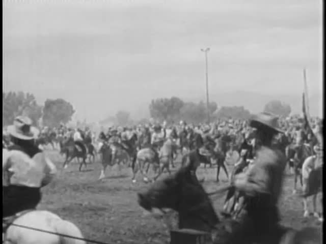 Cowboys on horseback prancing around before rodeo