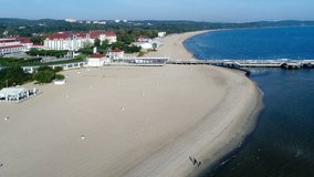 Sopot resort in Poland. Aerial flyby video of the beach, Gdansk Bay, Baltic Sea, wooden pier and vacation infrastructure. Early morning.