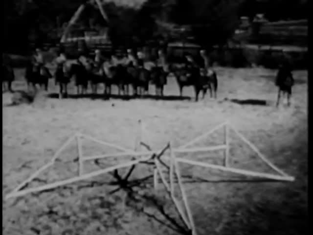 Cowboys on horseback jumping fence in a show ring