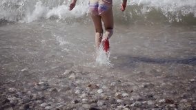 Baby girl having fun in the water outdoors. Happy child, happy girl plays in sea water. Summer fun. Slow motion video of 500 frames per second