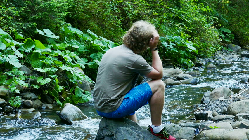 4K. Mountain  stream  in wood  and silhouette of man with smartphone.
