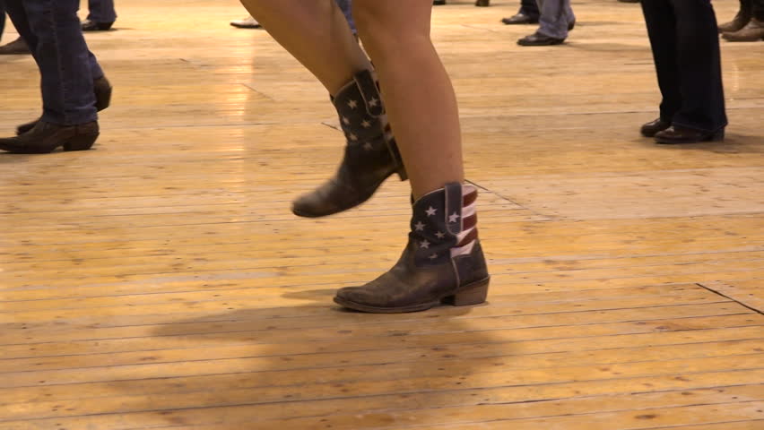 Woman dancing cowboy line dance at a folk country event, USA style. Female feet cowgirl stepping at American horse festival. Music tradition jeans boots and flag