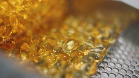 Production of pharmaceuticals and drugs, large number of gelatin capsules, amber color tablets on the conveyor, production line.
