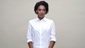 Nervous african woman in shirt moving and looking around over gray background