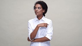 Pensive african woman in shirt looking around and having idea over gray background

