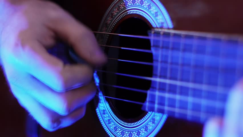 man playing guitar in the blue light