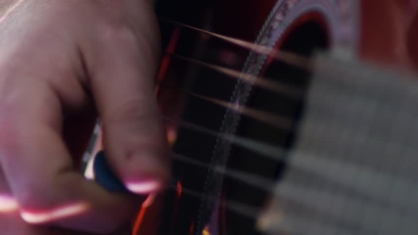 human playng an acoustic guitar closeup