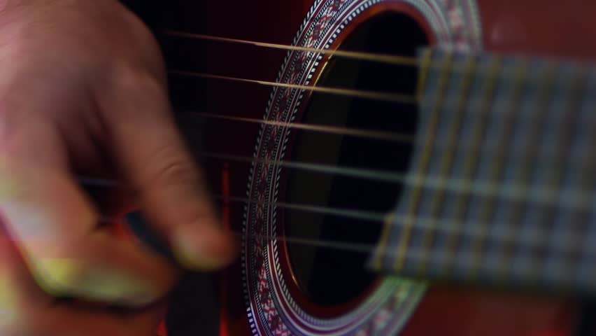 man playing an acouctic guitar in the light