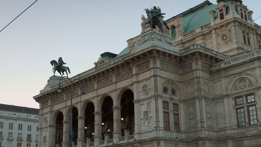 Slow tilt down the facade of the Vienna Opera House early evening in September as the city lights are coming on. Taken from Opernring