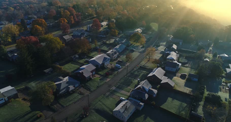 A slow reverse aerial establishing shot of a typical Western Pennsylvania residential neighborhood on a foggy late-Autumn morning. Pittsburgh suburbs. Shot at 60fps.  	