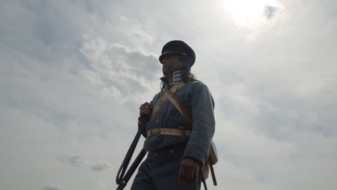 VIRGINIA - AUGUST 2017 - Mexican War Soldiers - Re-enactors, reenactment.  American Army Soldiers with musket rifles march through dusty Mexican desert, trudging, tired and wounded.  Silhouette in Sun