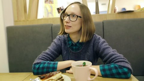 Negative emotion facial expression. Young girl with glasses is unhappy with her coffee and she is outraged and wants a refund. Woman is tired of tasteless food and bad drinks.