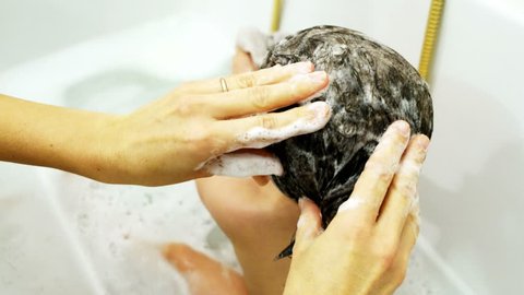 mother wash newborn hairs in the bathtub hygiene treatment head louse lice during bathe