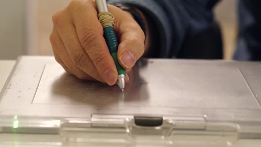 Male designer using a graphics tablet with stylus close-up view