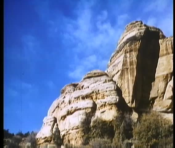 Panning shot of rocky mountains against blue sky
