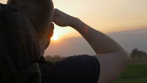 Close-up of young brave man looking at the distance. Determined and adventurous traveler hiking alone in nature and looking for new challenges outdoor at sunset. Concept of thinking about future.