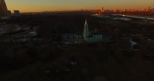 4K high quality aerial video scenic view of beautiful light blue church overlooking green park, distant city and hills in Krylatskoye area on quiet late afternoon near Moscow River in Moscow, Russia