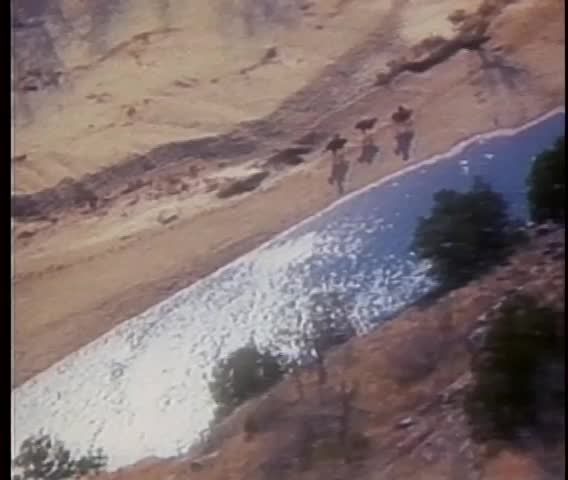 Aerial view of men on horses galloping alongside Buffalo River in Arkansas