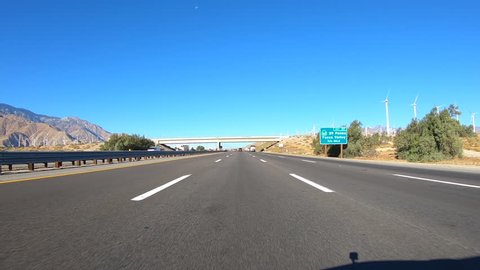 Palm Springs, California, USA - November 8, 2017:  Car mount driving time lapse past desert windmills on Interstate 10.