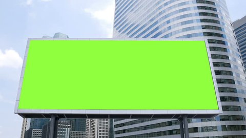 billboard with a blank green screen mock-up in front of office building in business district on a busy day, time lapse. footage for advertising background