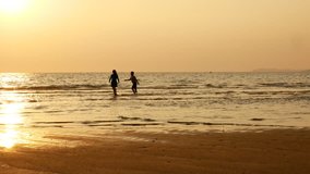 4K. silhouette of sister and brother running and playing in water at the beach on sunset. beauty and joyful teenager friends having fun, spraying over summer sunset.