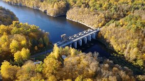 Aerial view of the dam on river with trees covered yellow foliage