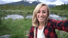 4k video, Young woman taking a selfie portrait by the mountain lake in Banff national park in Canada.
People sharing travel communication concept