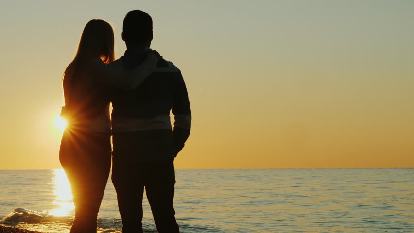 Silhouettes of a young couple hugging and admiring the sunset together by the sea. Back view | Shutterstock HD Video #32650846