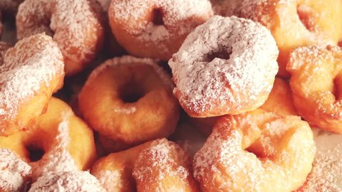 A large mountain of small donuts with powdered sugar. Smoothly rotate