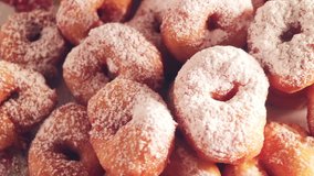 A large mountain of small donuts with powdered sugar. Smoothly rotate