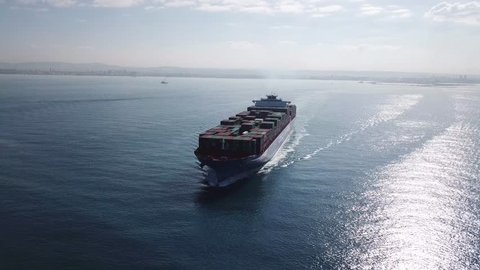 Huge large mega ULCV container ship sails on open water fully loaded with containers and cargo - aerial 4k view