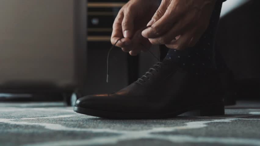 Unrecognizable businessman dressing up in a hotel room. Man tying his shoelaces. Close up. Slow motion. Royalty-Free Stock Footage #32666086