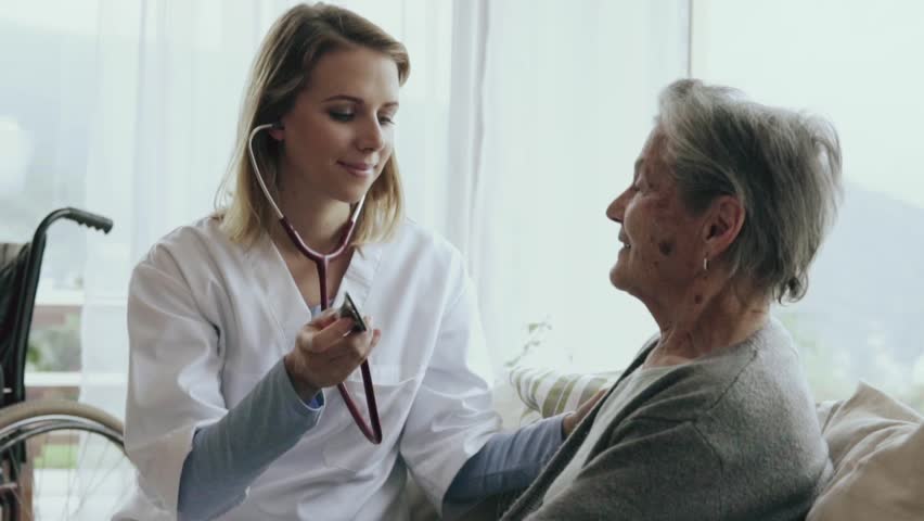 Health visitor and a senior woman during home visit. A female nurse or a doctor examining a woman. Slow motion.