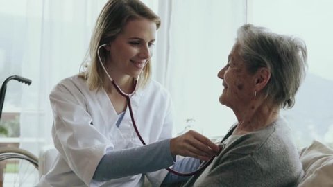 Health visitor and a senior woman during home visit. A female nurse or a doctor examining a woman. Slow motion.