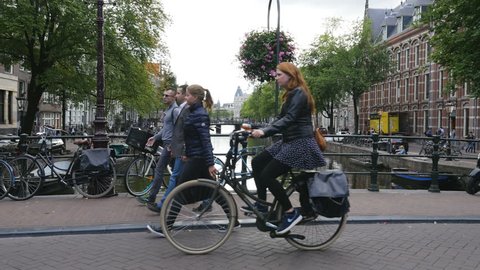 Amsterdam, Netherlands, June 2017. People biking and walking on bridge over the Kloveniersburgwal canal in Amsterdam. 