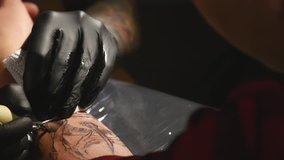 Tattoo artist make tattoo in studio, tattooing on the body.