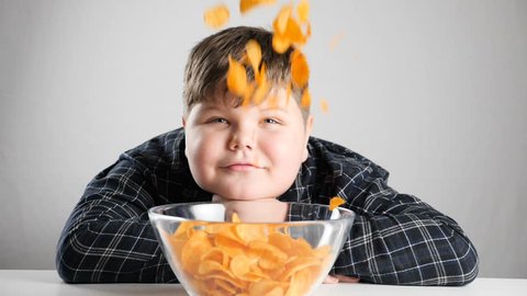 Young fat boy looks as chips are falling from the sky 50 fps slowmo